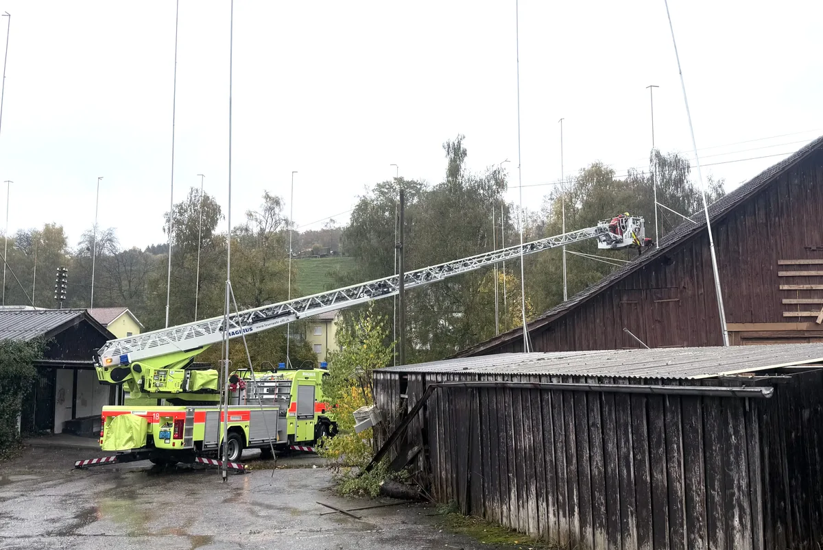Mithilfe der Autodrehleiter wurden lose Ziegel entfernt. Eine Autodrehleiter der Feuerwehr steht mit ausgefahrenem Arm vor einem holzigen Haus.